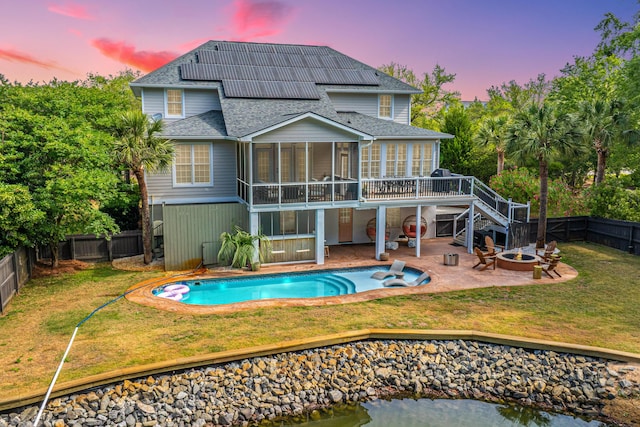 1143 Sea Eagle Watch, Charleston, SC 29412 - back of property at dusk with a sunroom, stairs, a fire pit, and a fenced backyard