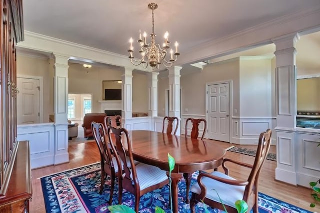 dining space with crown molding, a chandelier, light hardwood / wood-style flooring, and decorative columns