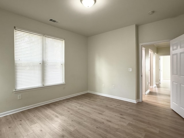 spare room with visible vents, wood finished floors, and baseboards