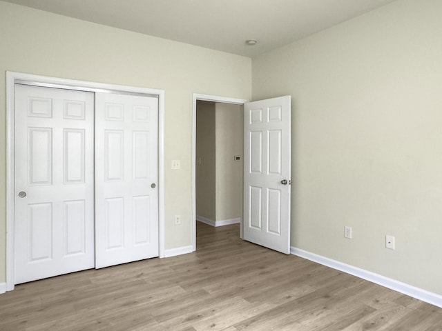 unfurnished bedroom with baseboards, light wood-style floors, and a closet