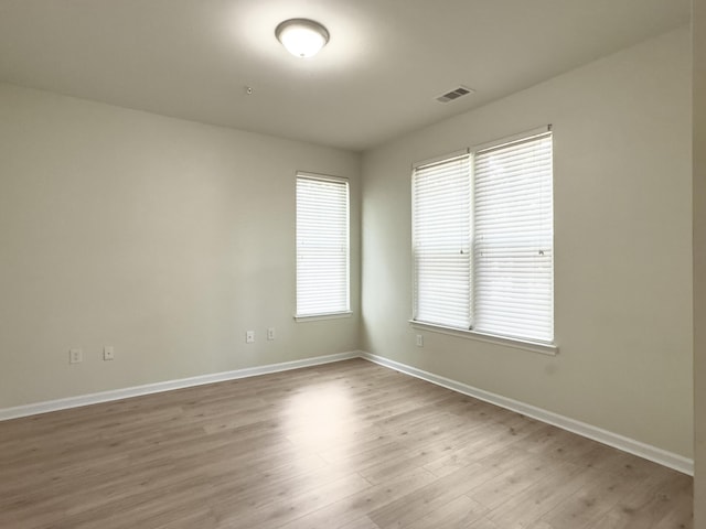 unfurnished room with baseboards, visible vents, and wood finished floors