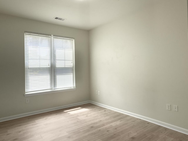 empty room featuring baseboards, a wealth of natural light, and light wood-type flooring
