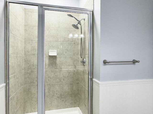 full bath featuring wainscoting and a shower stall