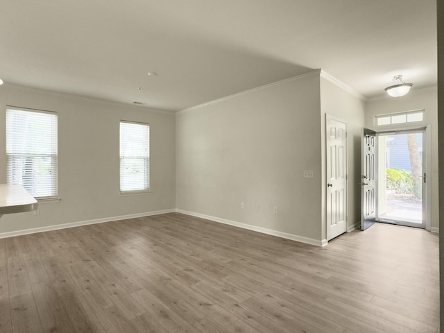 unfurnished living room with crown molding, wood finished floors, and baseboards
