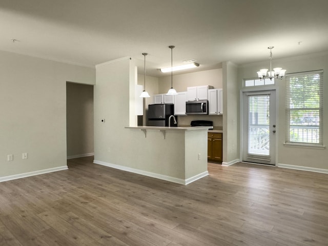 kitchen featuring stainless steel microwave, freestanding refrigerator, ornamental molding, an inviting chandelier, and open floor plan