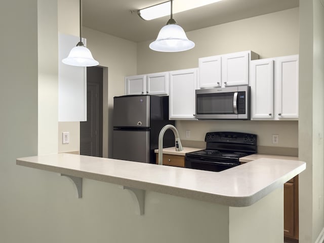 kitchen with a kitchen bar, a peninsula, stainless steel appliances, and light countertops