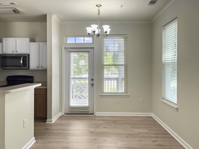 doorway with light wood-style floors, a healthy amount of sunlight, and a chandelier