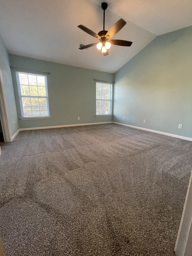 carpeted empty room featuring ceiling fan, a wealth of natural light, and lofted ceiling