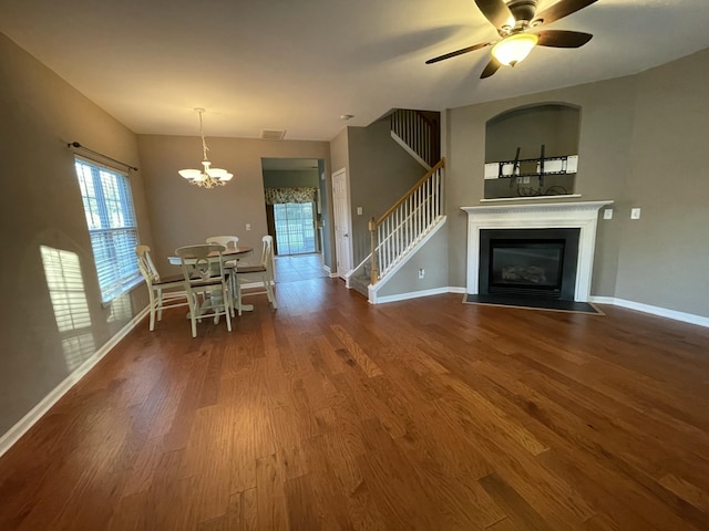 unfurnished living room with ceiling fan with notable chandelier and hardwood / wood-style floors