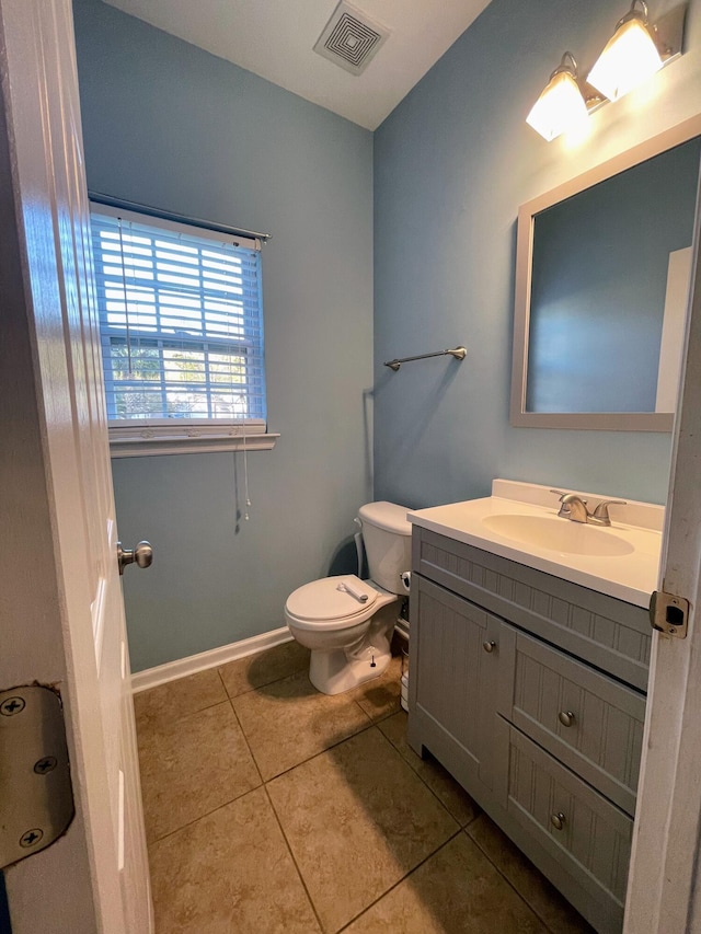 bathroom with toilet, vanity, and tile patterned flooring