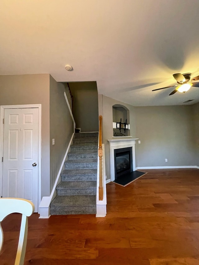 staircase with ceiling fan and hardwood / wood-style flooring