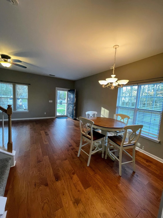 dining space with ceiling fan with notable chandelier and hardwood / wood-style flooring