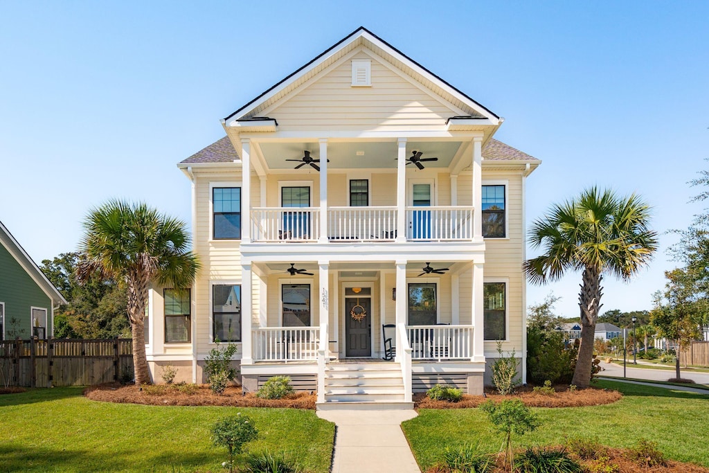 view of front facade with a porch, a front lawn, ceiling fan, and a balcony