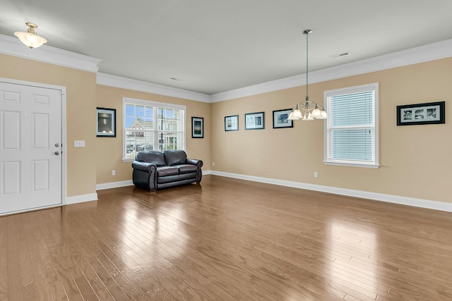 unfurnished room featuring wood finished floors, baseboards, visible vents, crown molding, and a notable chandelier