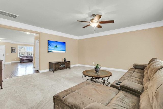 carpeted living room featuring visible vents, crown molding, baseboards, wood finished floors, and a ceiling fan