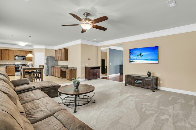 living area with ceiling fan, visible vents, baseboards, and ornamental molding