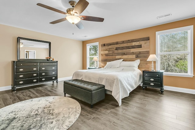 bedroom featuring visible vents, baseboards, wood finished floors, and a ceiling fan