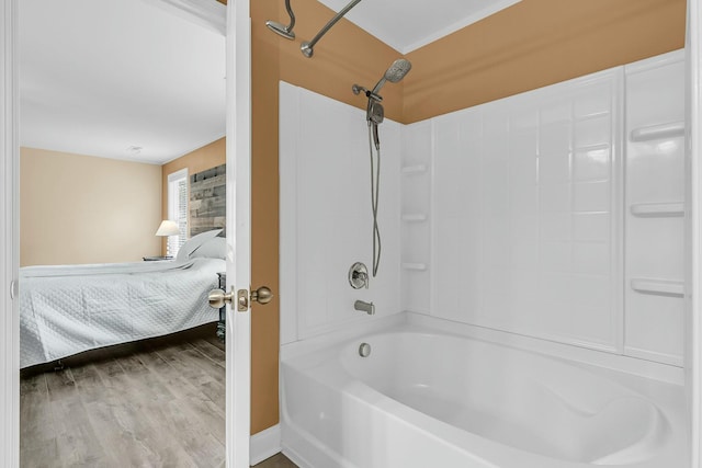 ensuite bathroom with bathtub / shower combination, ensuite bath, and wood finished floors