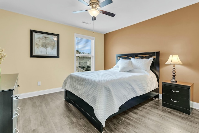 bedroom featuring visible vents, ceiling fan, baseboards, and wood finished floors