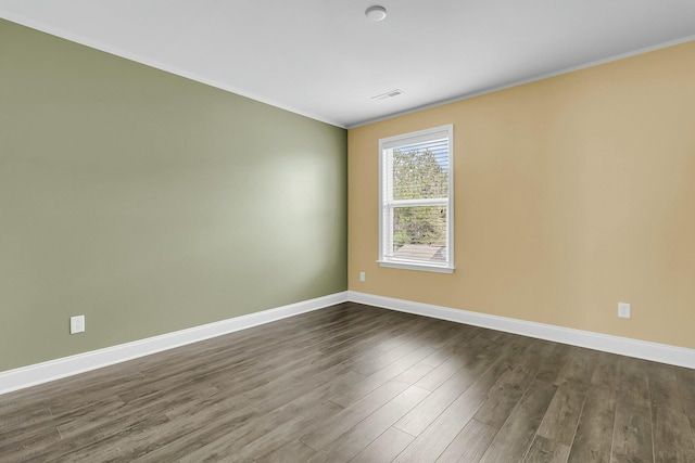 empty room with visible vents, baseboards, and dark wood-type flooring