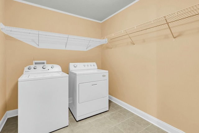 laundry room with ornamental molding, light tile patterned floors, baseboards, laundry area, and washing machine and clothes dryer