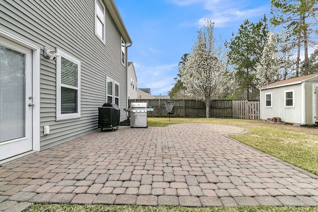 view of patio with grilling area, an outbuilding, a fenced backyard, and a shed