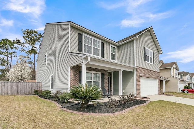 traditional home with driveway, fence, a front yard, a garage, and brick siding