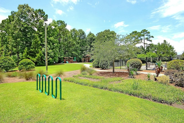 view of property's community with fence, playground community, and a lawn