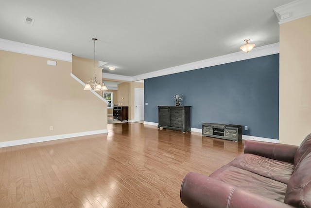 living room with an inviting chandelier, wood finished floors, baseboards, and ornamental molding