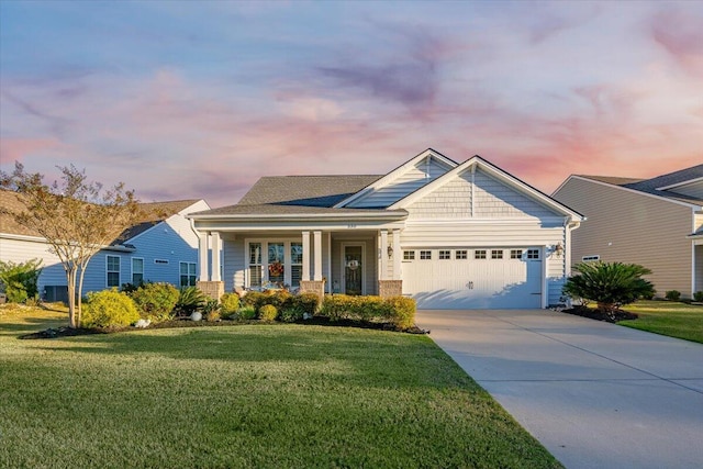 view of front of property featuring a garage, covered porch, and a lawn