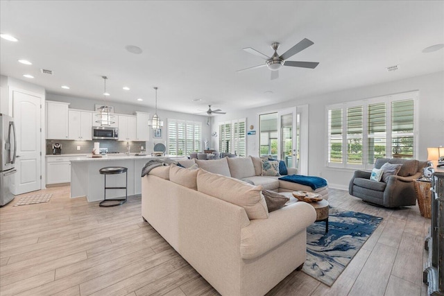 living room with ceiling fan and light wood-type flooring