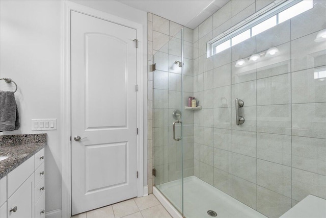 bathroom featuring tile patterned floors, a shower with shower door, and vanity