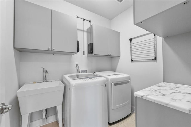 laundry area with cabinets, washer and clothes dryer, sink, and light tile patterned floors