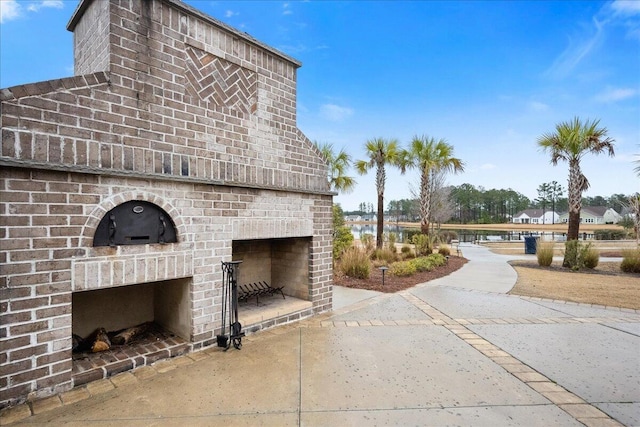 view of side of property with an outdoor brick fireplace and a water view