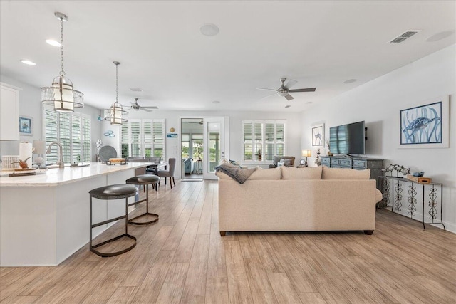 living room featuring ceiling fan, light hardwood / wood-style floors, and a healthy amount of sunlight