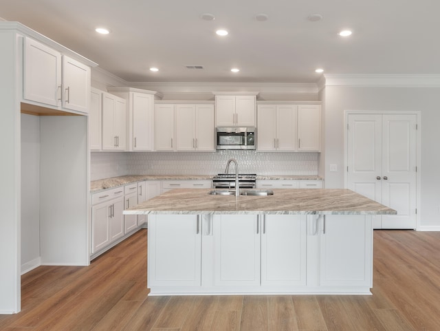 kitchen featuring white cabinetry, stainless steel microwave, and a sink