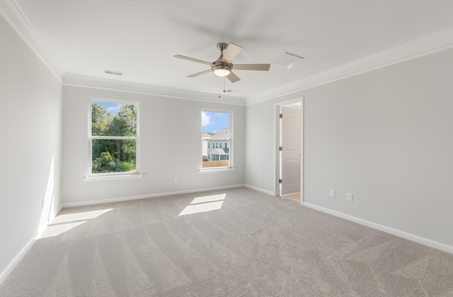 carpeted spare room featuring visible vents, baseboards, ornamental molding, and a ceiling fan