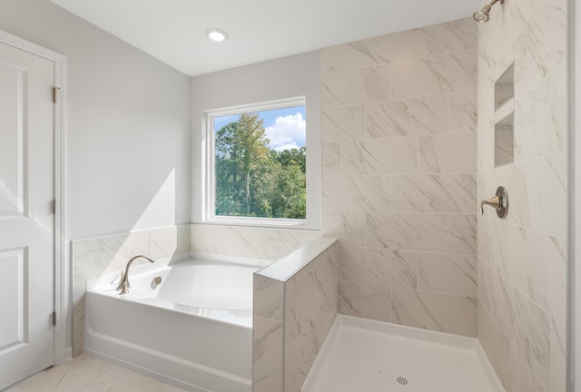 bathroom featuring marble finish floor, a bath, and a tile shower