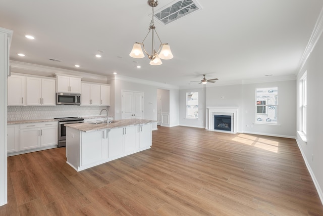 kitchen featuring visible vents, a fireplace with flush hearth, a sink, stainless steel appliances, and white cabinetry