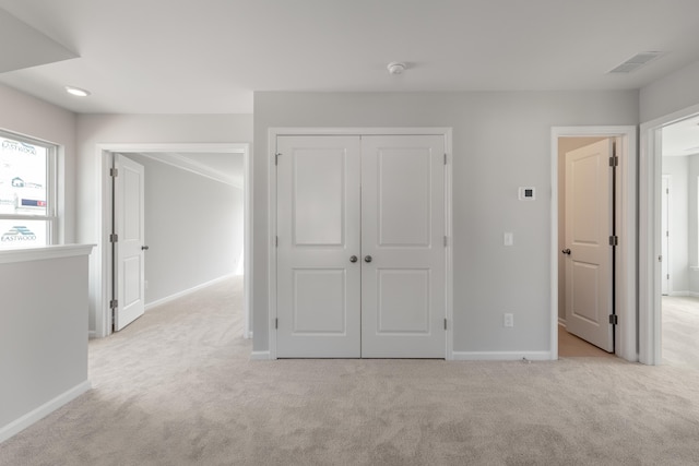 unfurnished bedroom featuring visible vents, light carpet, and baseboards