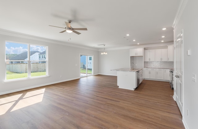 kitchen with ornamental molding, a sink, backsplash, wood finished floors, and open floor plan