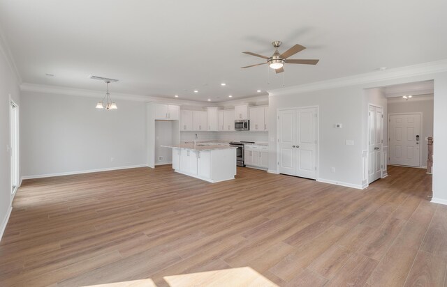 kitchen with light wood-type flooring, appliances with stainless steel finishes, open floor plan, and white cabinetry