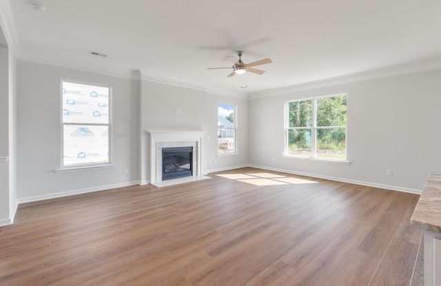 unfurnished living room with visible vents, light wood-style flooring, a tiled fireplace, and crown molding