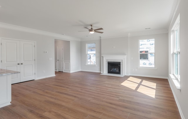 unfurnished living room with a fireplace with flush hearth, a ceiling fan, light wood-type flooring, and ornamental molding