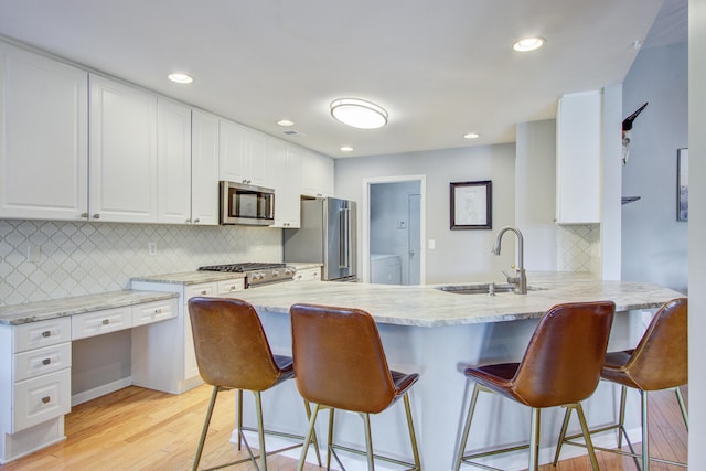 486 Maple Oak Ln, Charleston, SC 29414 - kitchen with high end appliances, a sink, a peninsula, light wood-style floors, and white cabinetry