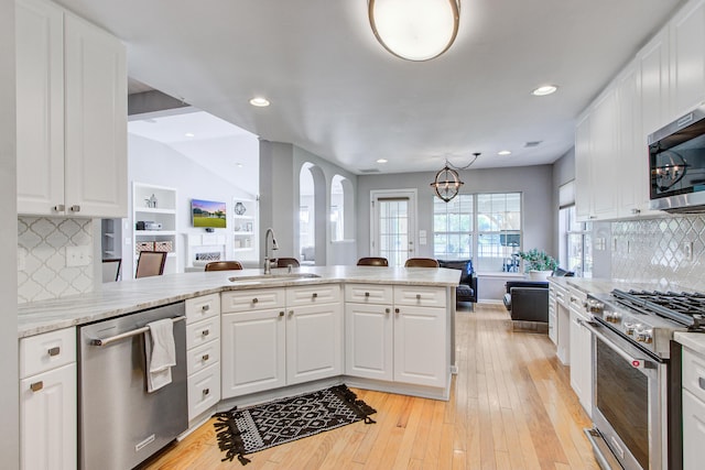 486 Maple Oak Ln, Charleston, SC 29414 - kitchen featuring stainless steel appliances, a sink, white cabinets, decorative backsplash, and vaulted ceiling