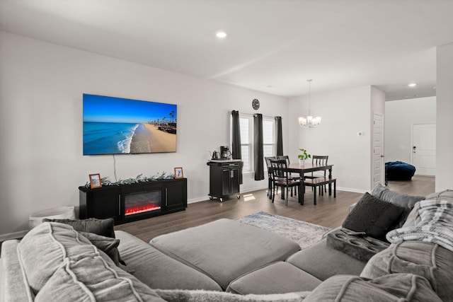 living room featuring a chandelier, recessed lighting, wood finished floors, baseboards, and a glass covered fireplace