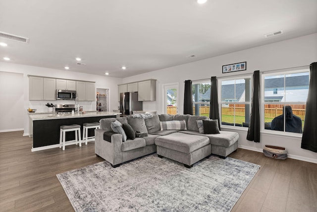 living area with recessed lighting, wood finished floors, and baseboards