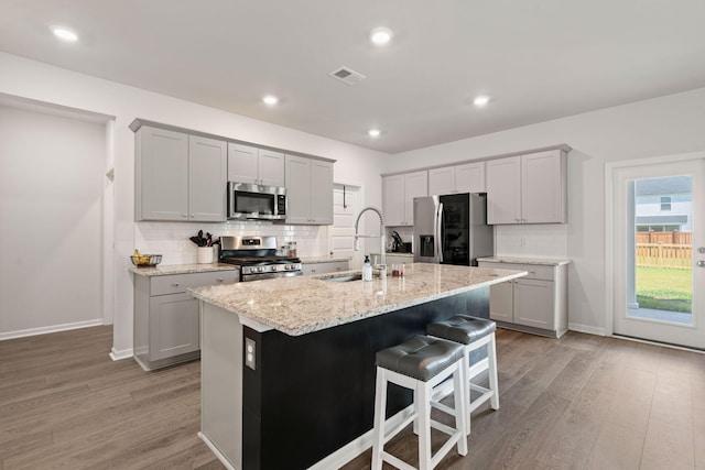 kitchen with stainless steel appliances, a sink, light wood-style floors, tasteful backsplash, and recessed lighting