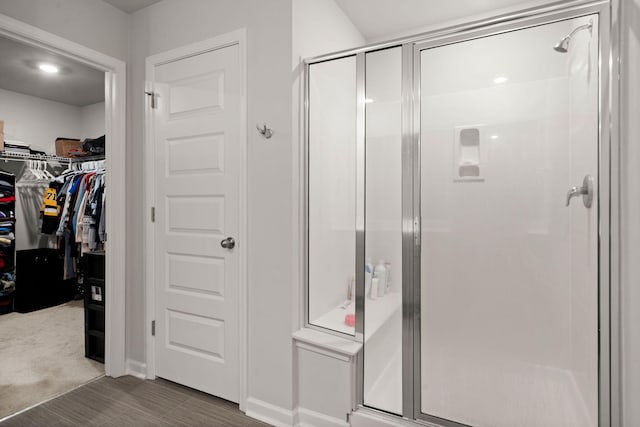 bathroom featuring a stall shower, a spacious closet, and wood finished floors